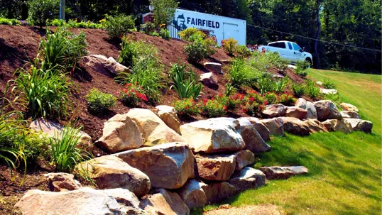 A beautifully landscaped hillside showcases a rock retaining wall with vibrant plants.