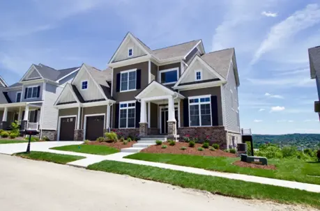 A modern two-story home with brown siding and a well-landscaped green lawn, illustrating excellent curb appeal and property value.