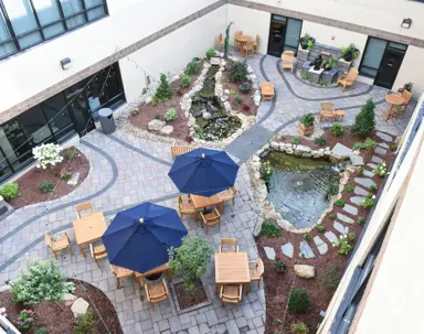 This image showcases a beautifully landscaped courtyard. It features two tiered ponds, multiple seating areas, and abundant greenery.