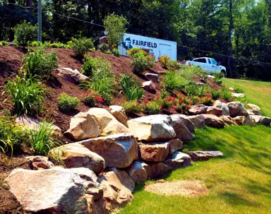 A newly landscaped hillside features rock retaining walls and fresh plantings.